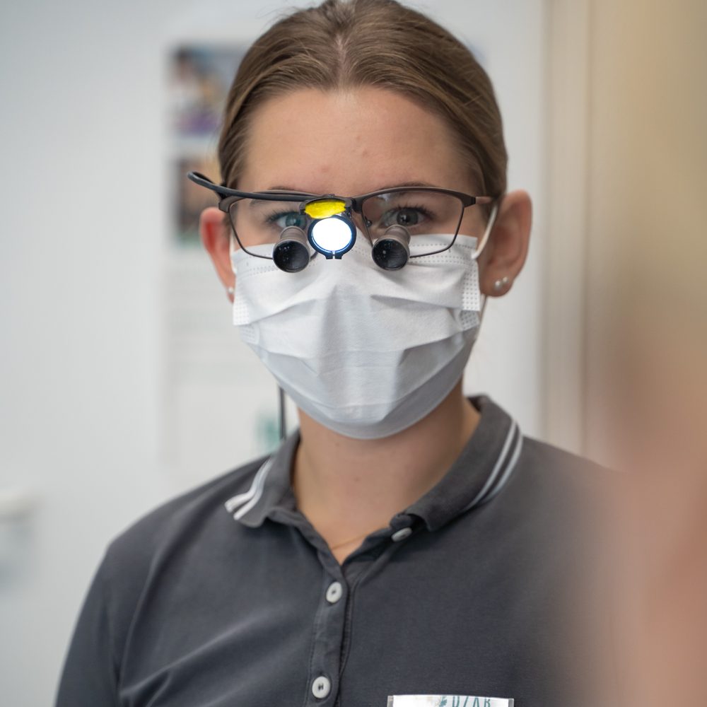 Zahnmedizinische Fachangestellte mit Lupenbrille im Behandlungszimmer